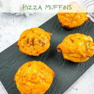 Pizza muffins on a black platter.