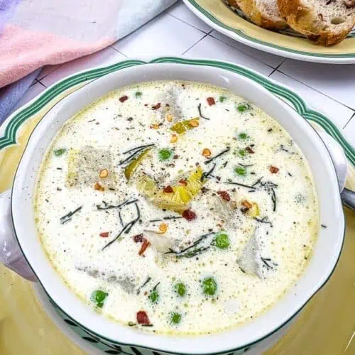 Potato & Pea Chowder in a bowl with bread in the background.
