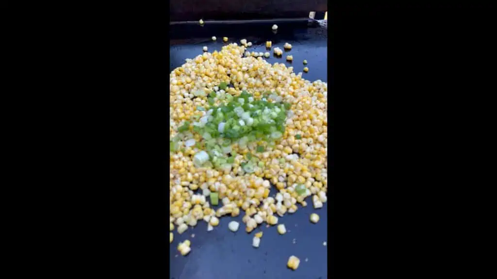 Green onions and garlic added to corn on the griddle.