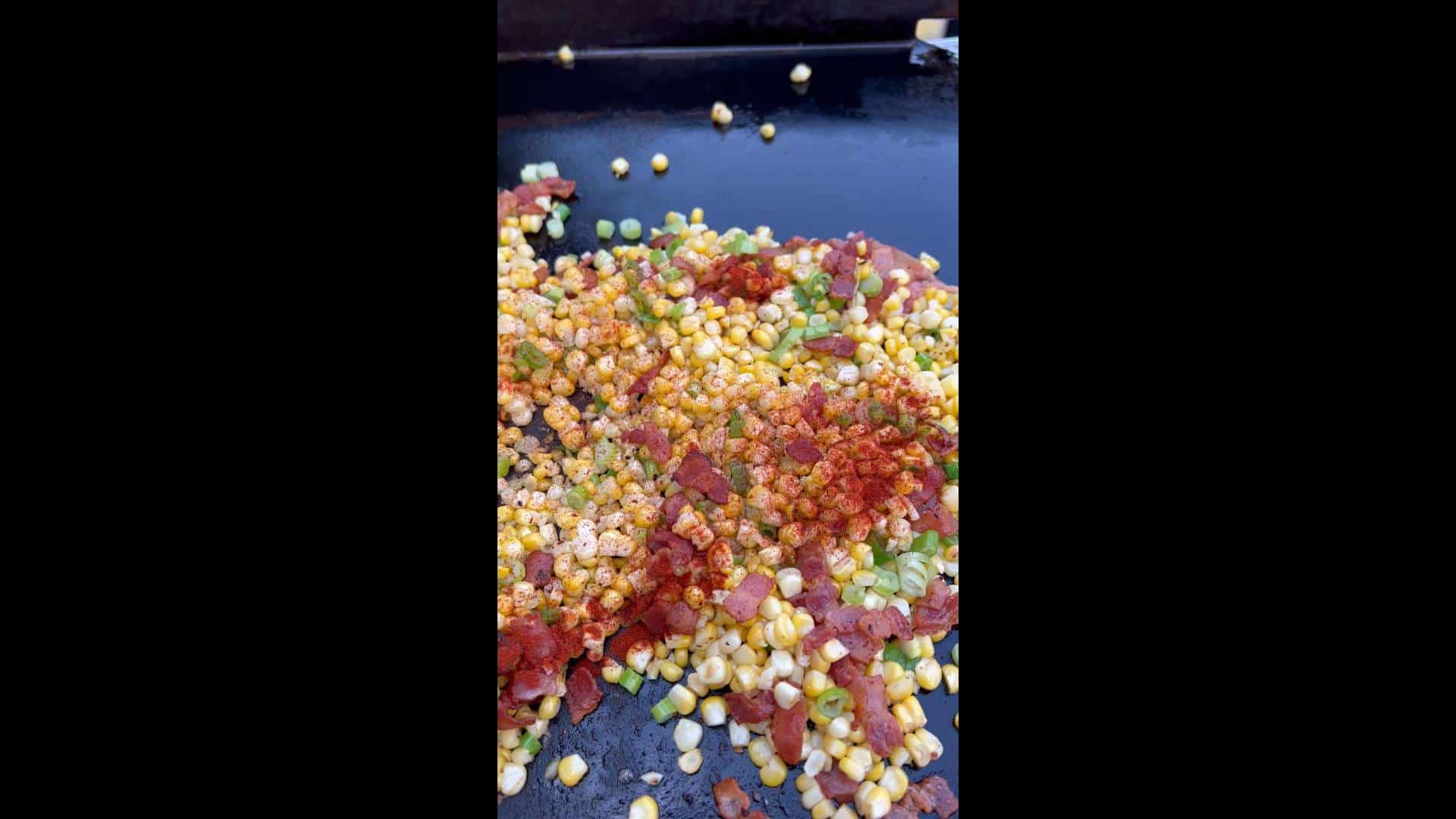 Seasoning added to Bacon-Fried Corn on the griddle.