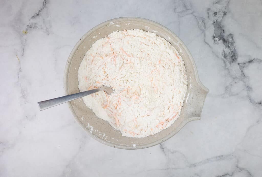 Dry ingredients mixed with cheese in a bowl.
