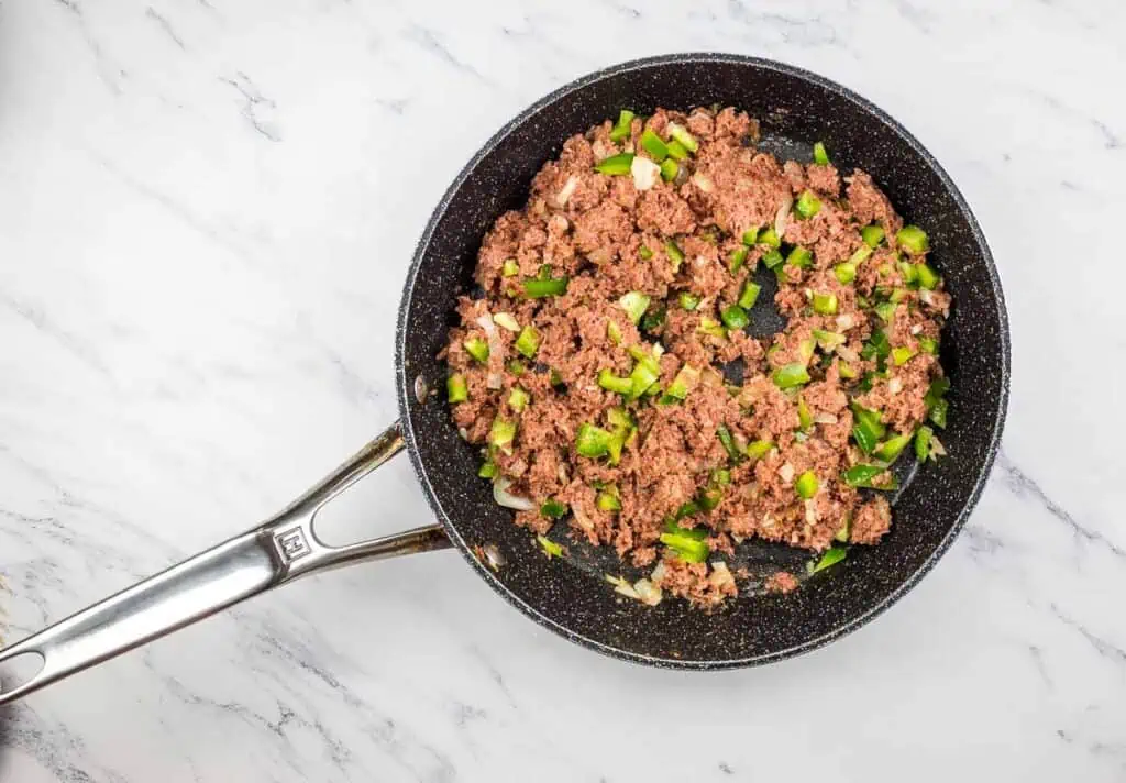 Peppers and corned beef added to the skillet.