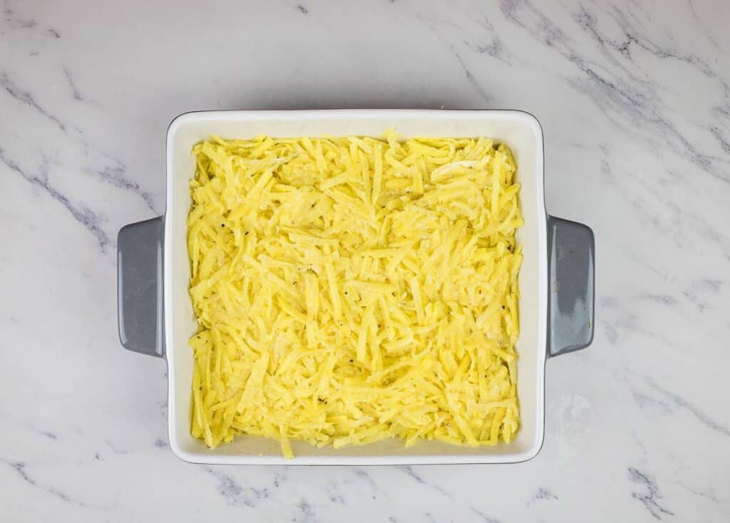 Potato mixture in the bottom of the casserole dish.
