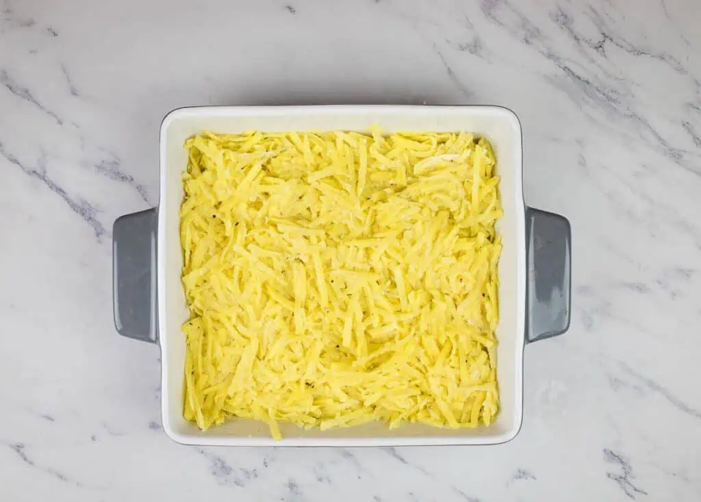 Potato mixture in the bottom of the casserole dish.