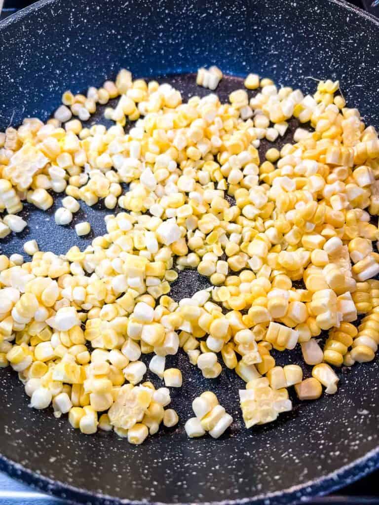 Corn niblets cooking in a skillet.