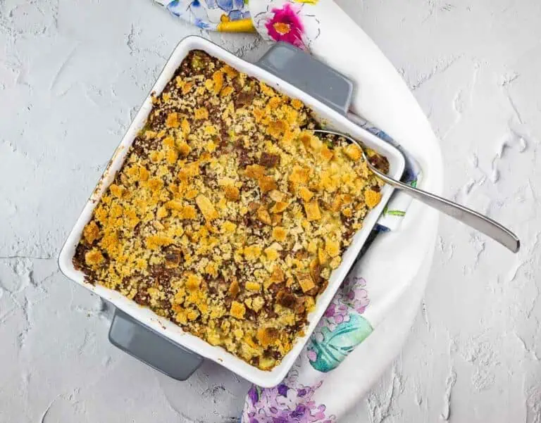 A canned corned beef hash casserole in a white dish with a spoon.