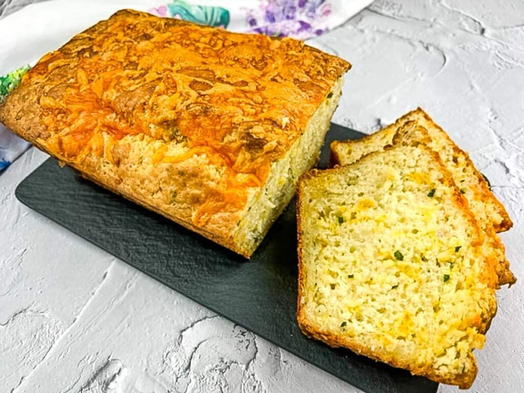 A horizontal image of sliced Potato Cheese Bread on a black platter.