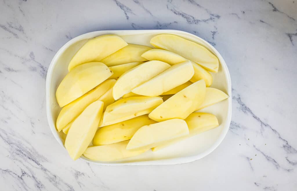 Potatoes cut into wedges on a plate.