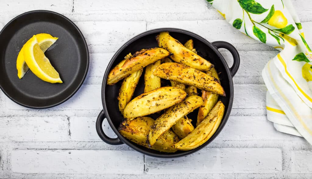 A top-down shot of Greek Lemon Potatoes in a black bowl.