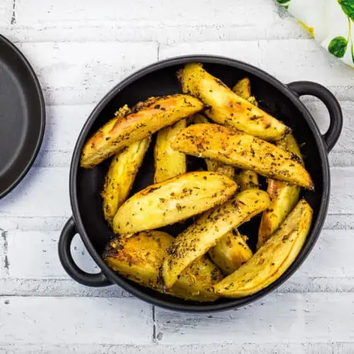 A top-down shot of Greek Lemon Potatoes in a black bowl.
