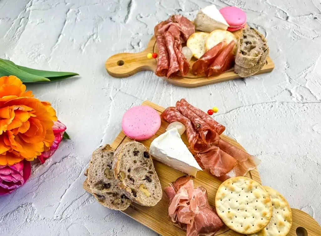 Individual charcuterie boards with flowers nearby.