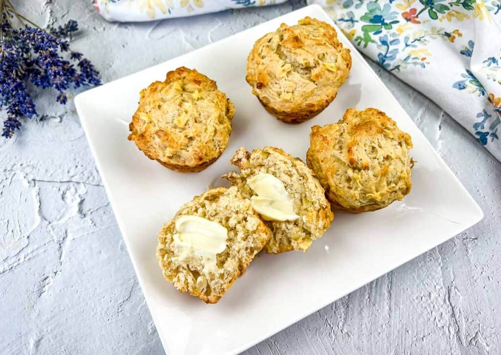 Sliced muffins with a dab of butter on a white plate.