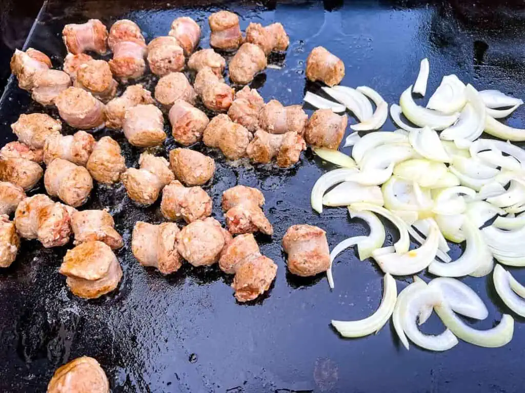 Onions cooking next to the sausage.