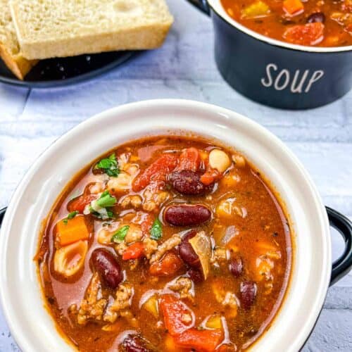 Pasta e Fagioli Soup in 2 bowls with cheese nearby.