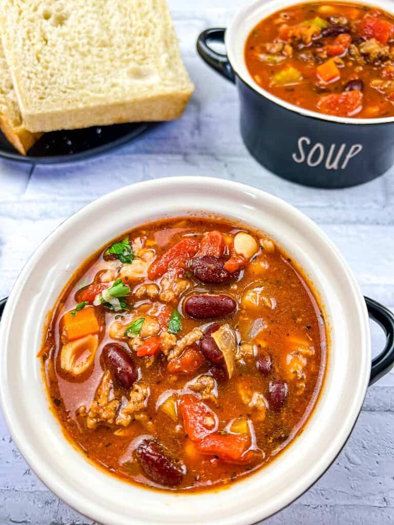 Pasta e Fagioli Soup in 2 bowls with cheese nearby.
