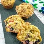 Rhubarb-Blueberry Muffins on a plate with a cut muffin in the front.