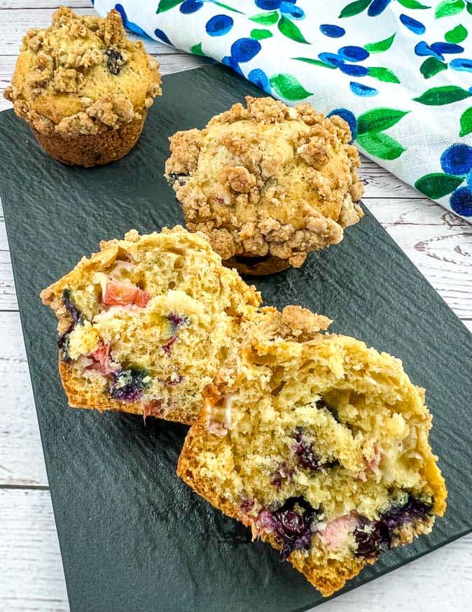 Rhubarb-Blueberry Muffins on a plate with a cut muffin in the front.