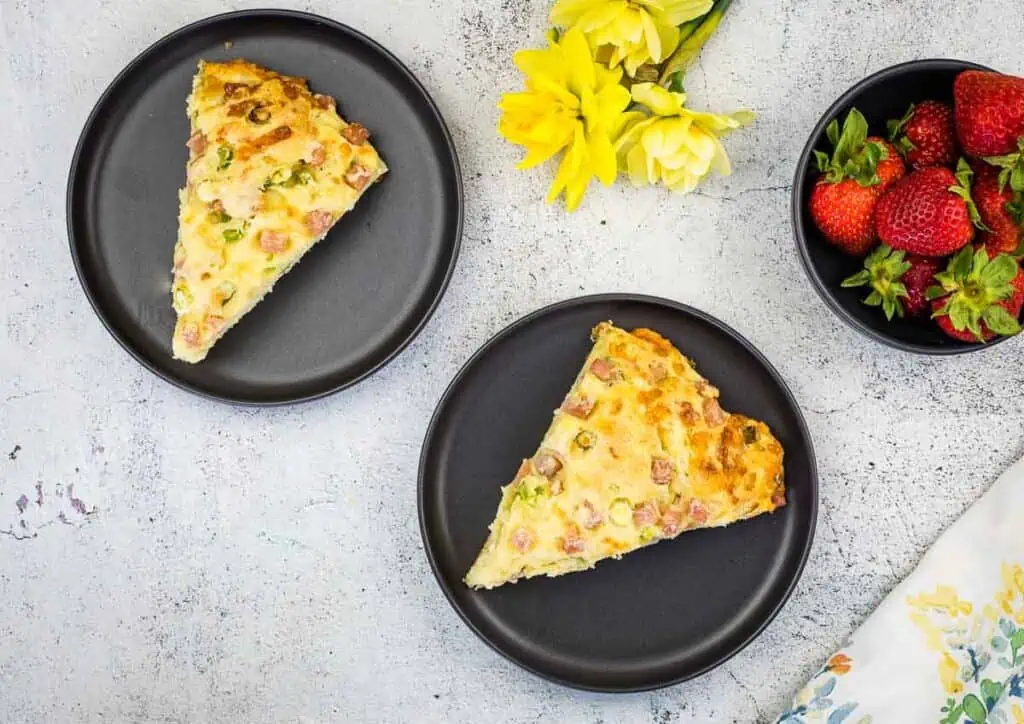 A top-down shot of two Ham & Cheese Scones on black plates.