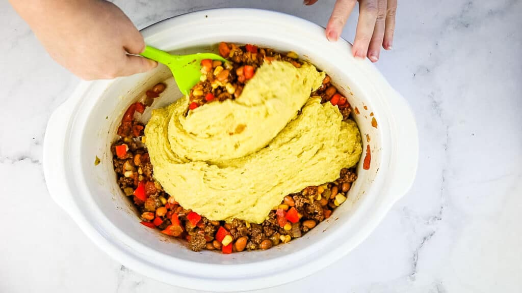 Cornbread mixture on top of the ingredients.