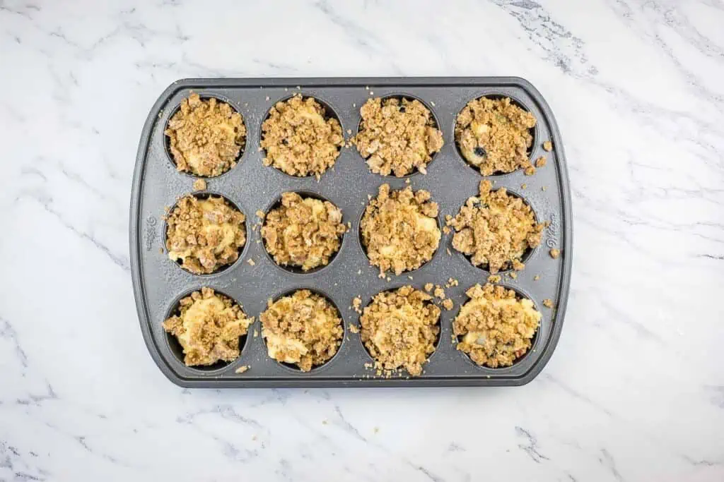 Muffin batter in tin topped with streusel crumb.