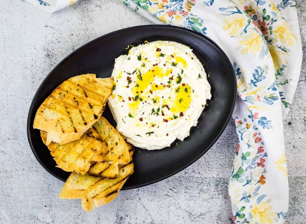 Whipped feta on a plate with grilled bread.