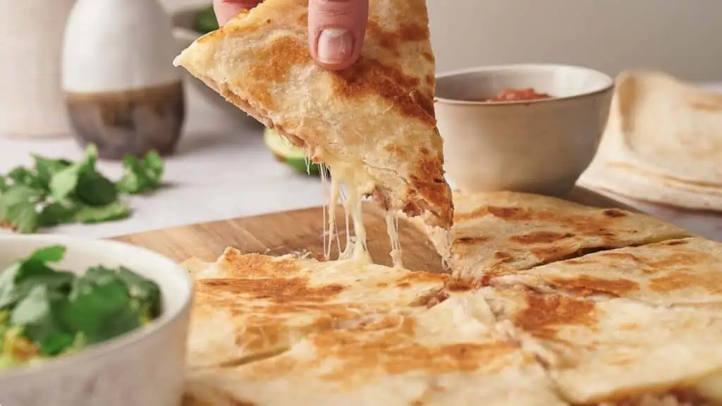 Someone taking a slice of cheese quesadilla.