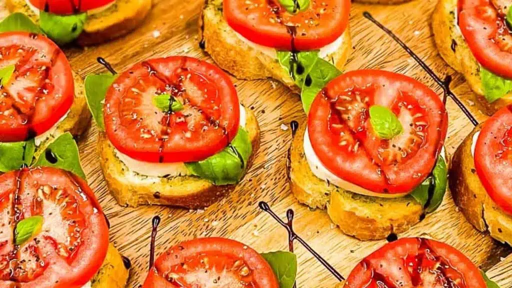Caprese bites on a serving board, drizzled with balsamic glaze.