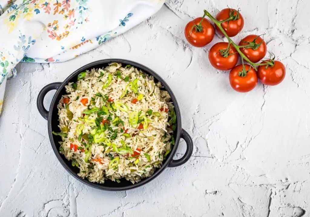 A top down shot of Mediterranean Rice on a counter with tomatoes.