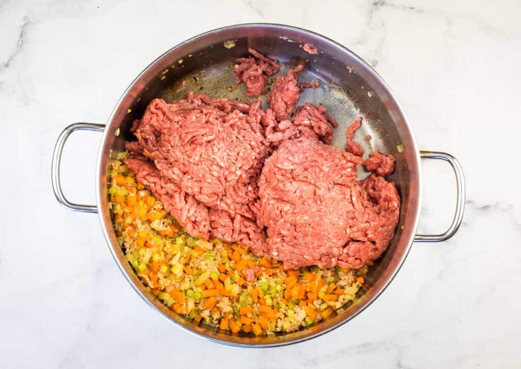 Meat added to the pot with the vegetables.