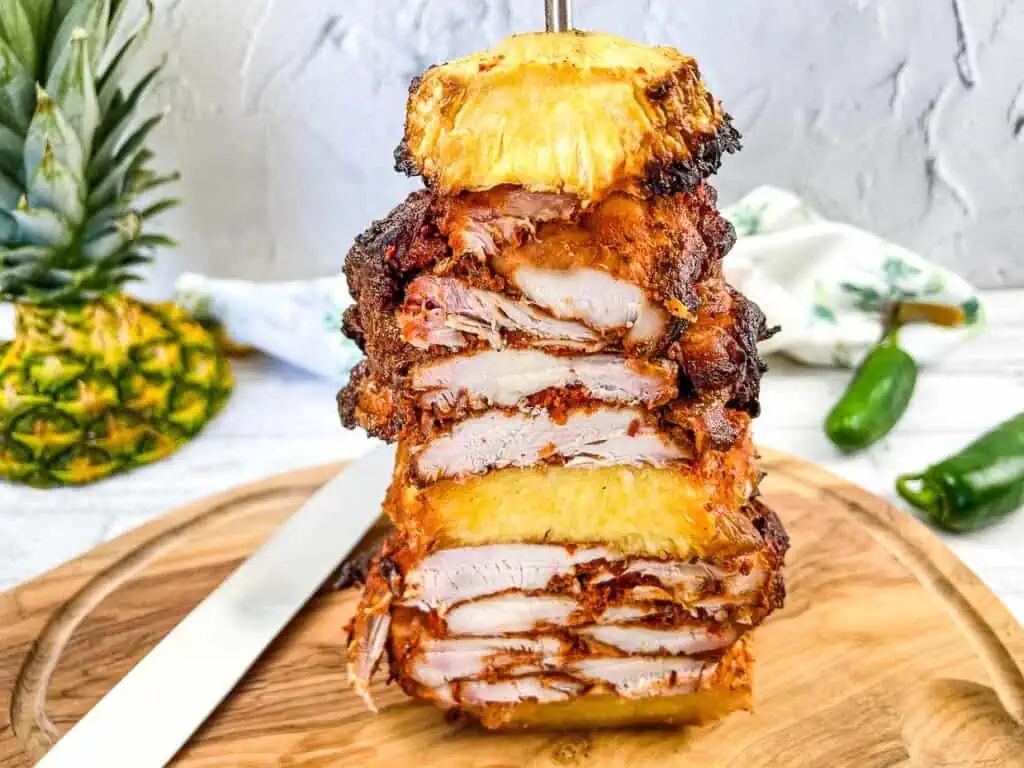 A horizontal image of Smoked Chicken Al Pastor on a vertical skewer.