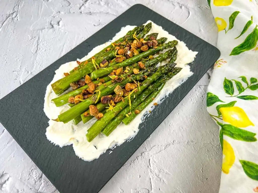 A horizontal shot of Asparagus with Mascarpone on a black platter.