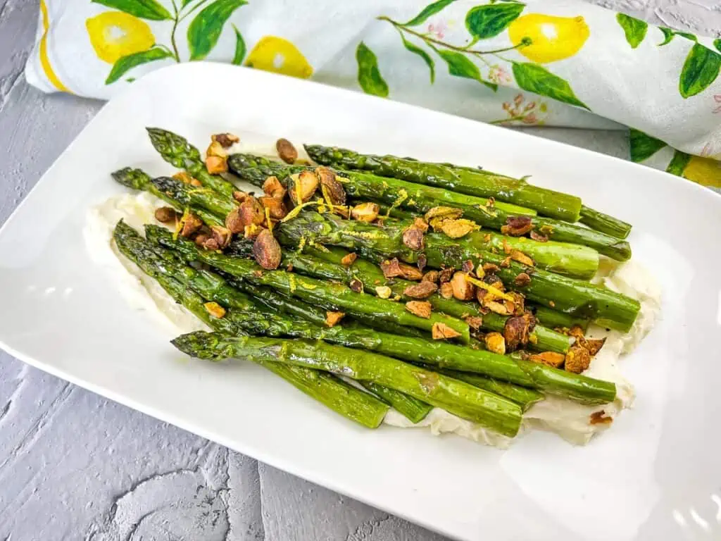 Cooked asparagus topped with pistachios on a bed of mascarpone cheese.