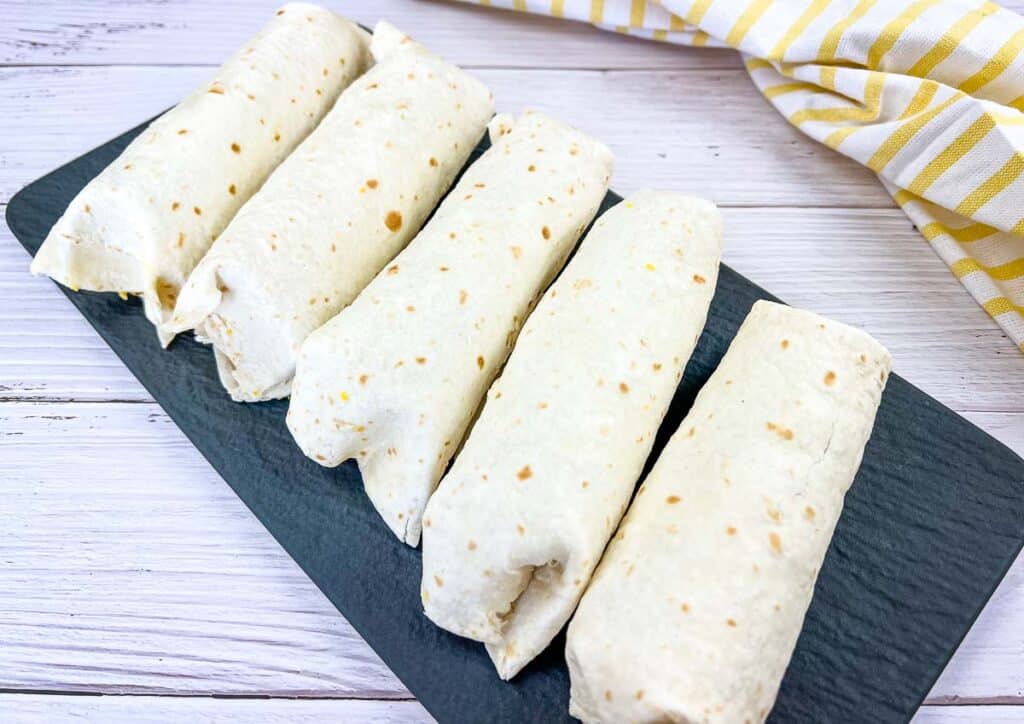 Breakfast burritos on a black platter.