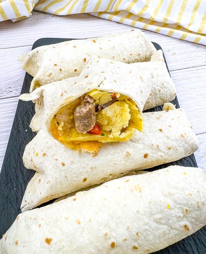 Freezer Breakfast Burritos lined up with one cut in half.