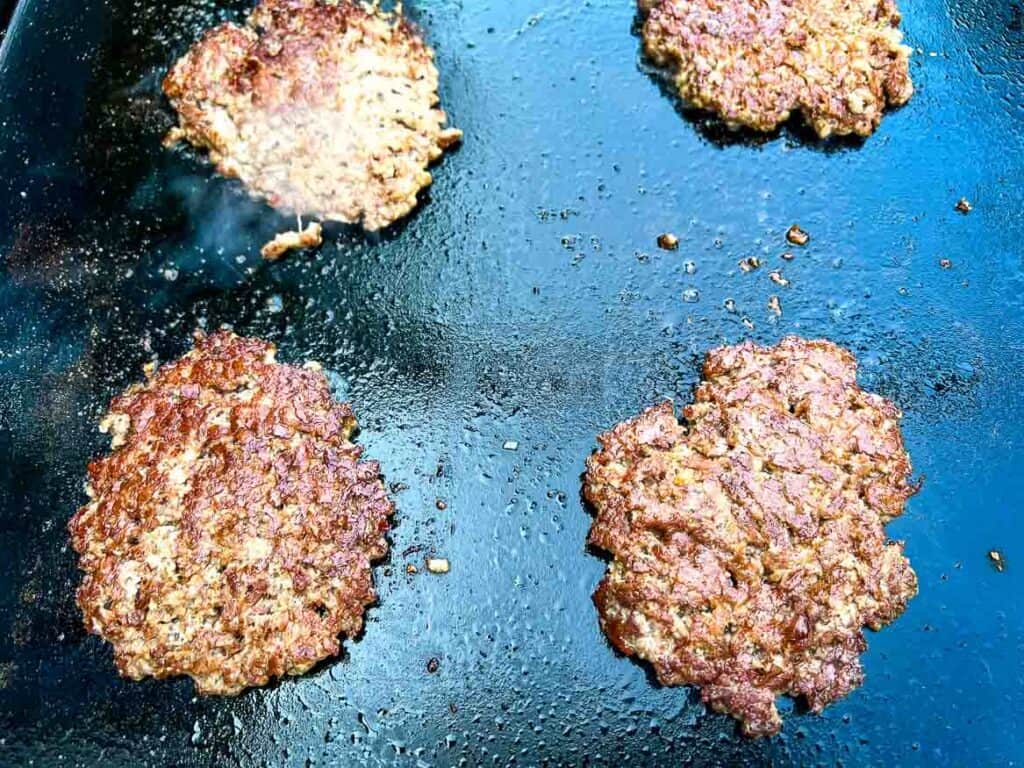 Seasoned and cooked patties on a griddle.