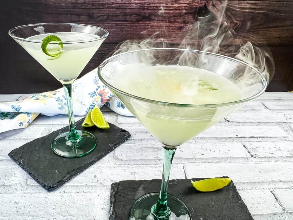 A horizontal shot of a smoked gimlet with a second in the background.