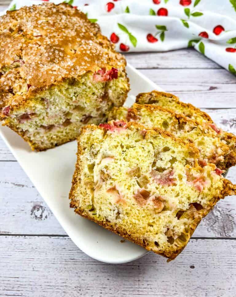 Best Rhubarb Bread on a platter with a few slices in the front.