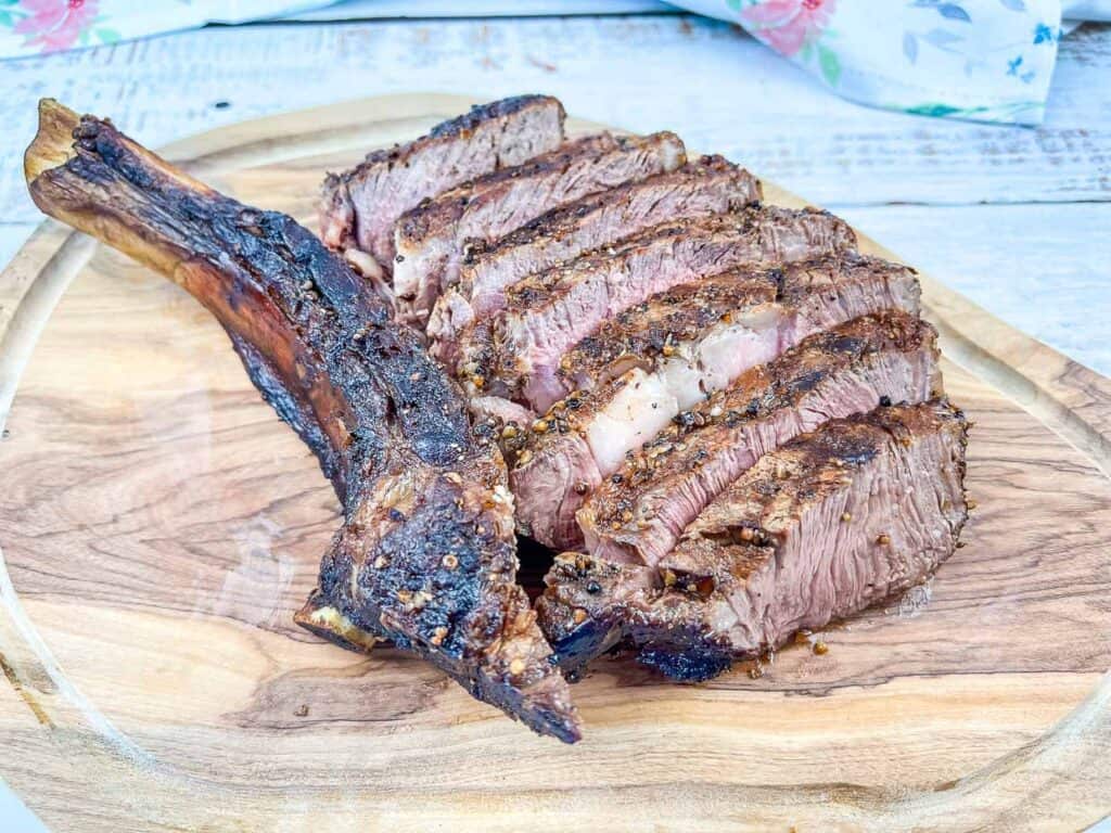 A sliced tomahawk steak on a cutting board.