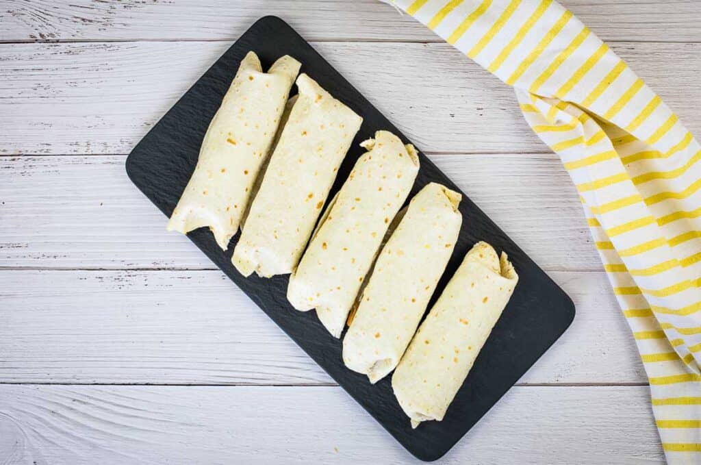 A top-down shot of Freezer Breakfast Burritos on a black platter.