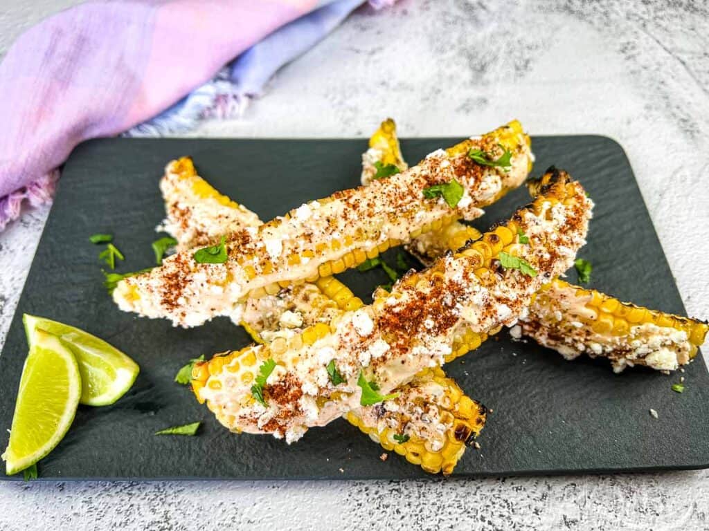 Sauced corn ribs on a black serving plate.
