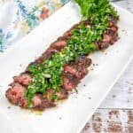 Grilled Hanger Steak with Chimichurri on a white platter.