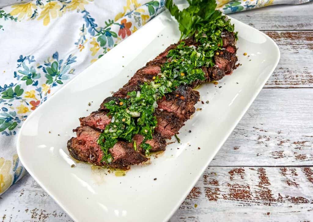 Grilled hanger steak with chimichurri on a platter.