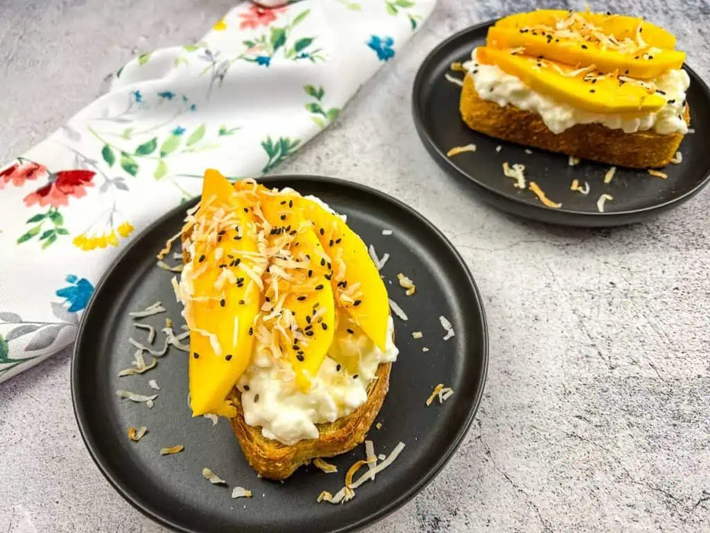 A horizontal shot of Cottage Cheese Toast with Mango & Coconut on black plates.
