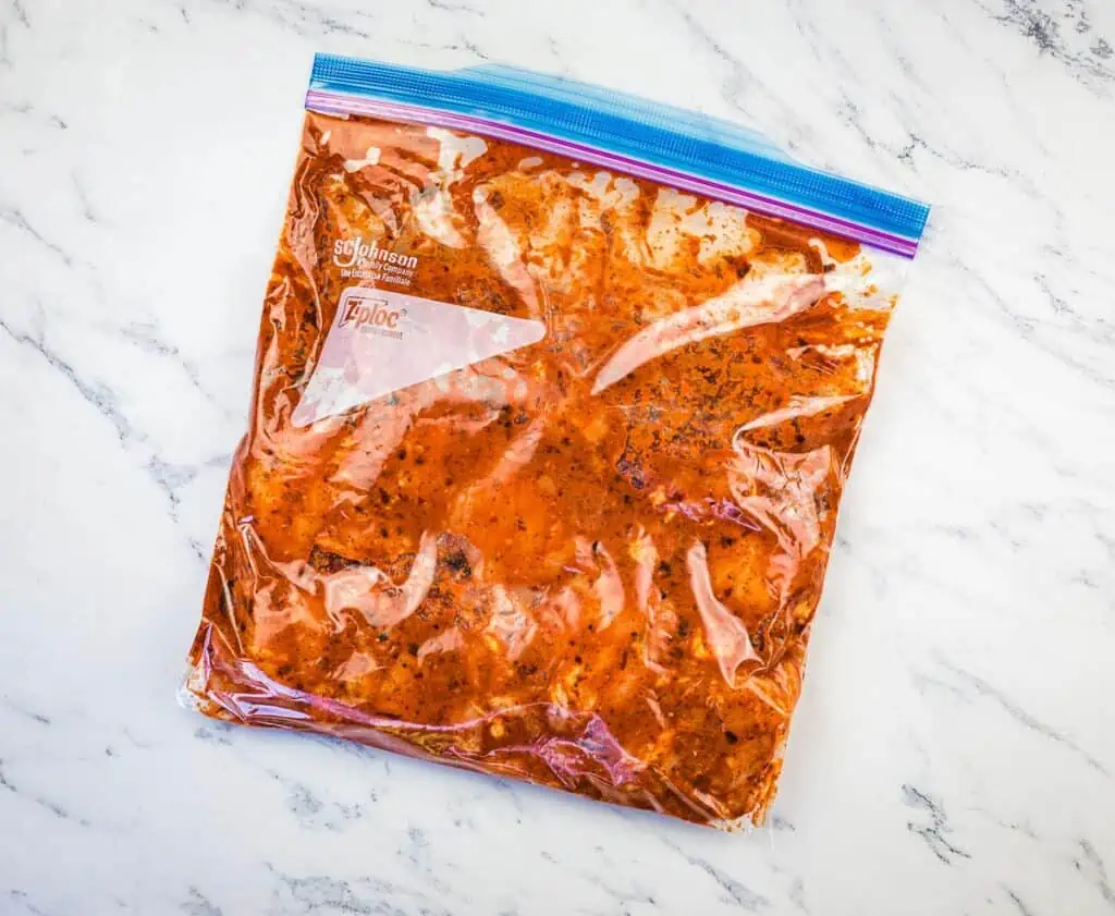 Chicken marinating in a bag.