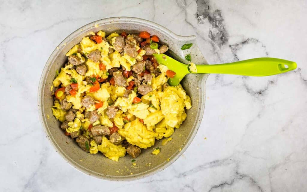 Cooked eggs and sausage mixed in a bowl.