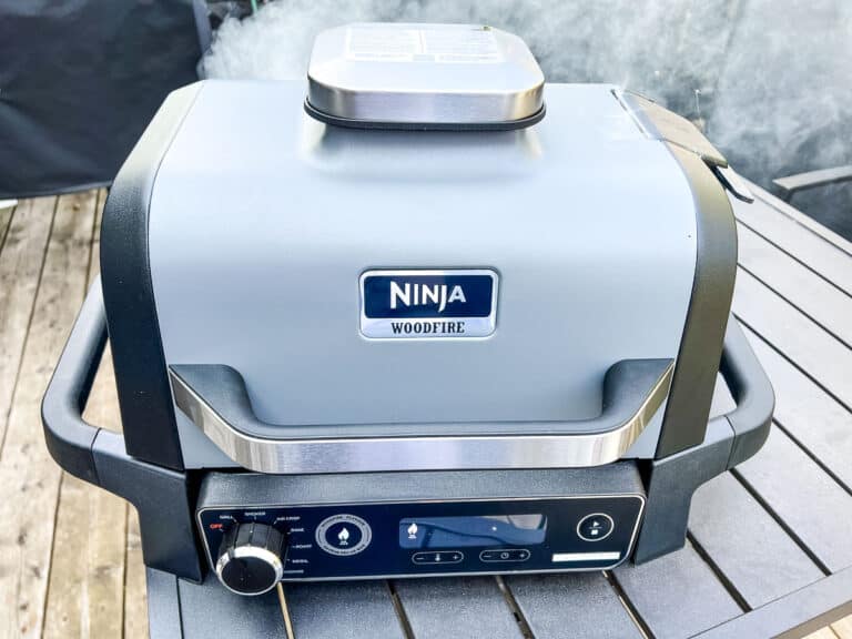 An image of a closed Ninja Woodfire Grill with smoke coming out of it.