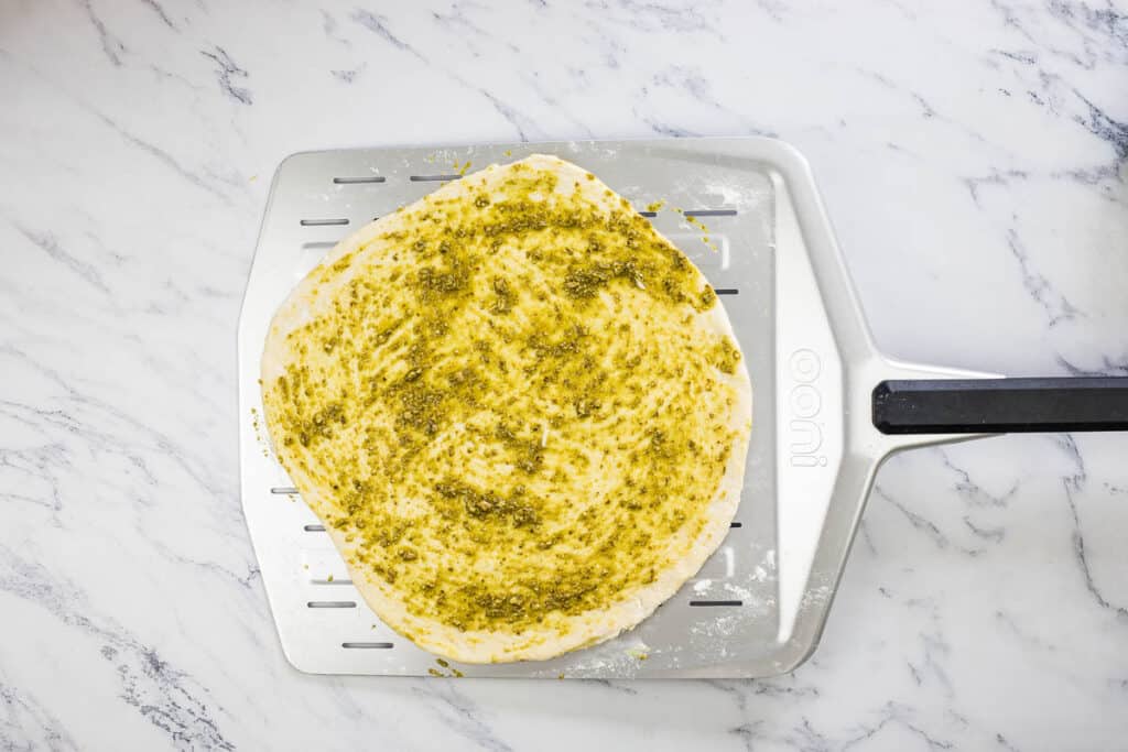 Top the dough with the pesto sauce.