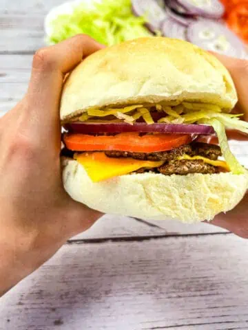 A Blackstone Smash Burger held between 2 hands.