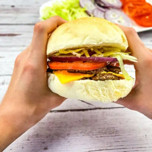 A Blackstone Smash Burger held between 2 hands.