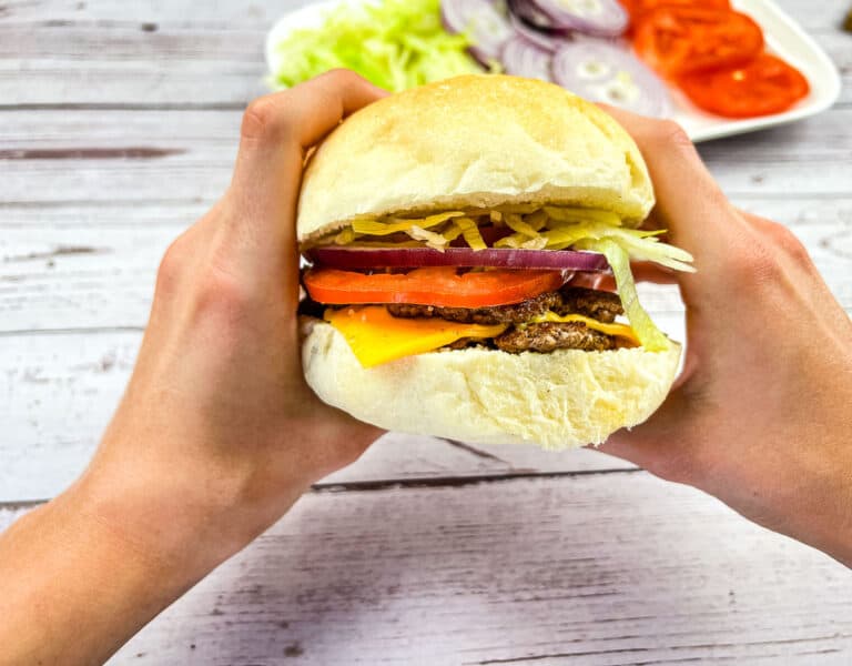 A Blackstone Smash Burger held between 2 hands.